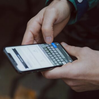 Person typing on a smartphone while navigating a website on mobile, illustrating a mobile menu or navigation issue.